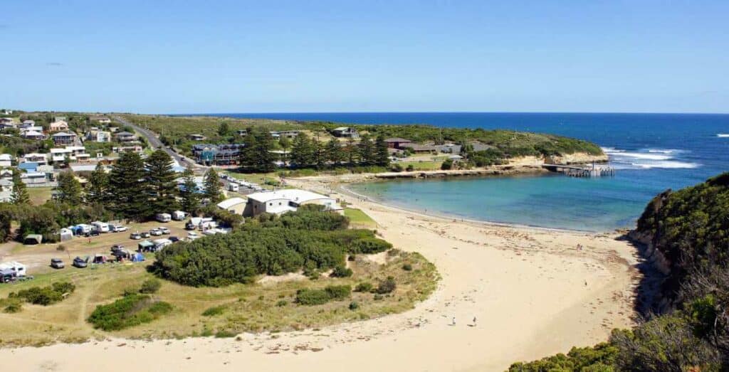 Aerial view of a coastal town and beach along the Great Ocean Road, a popular destination for road trips in Australia.
