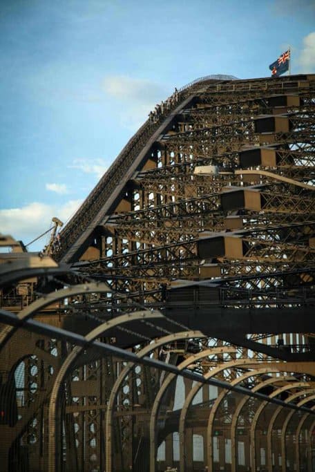 Side angle of tourists walking on the Sydney Harbour Bridge's upper arch, demonstrating the structure's impressive capacity, linked to the topic of "how much weight can the Sydney Harbour Bridge hold?"