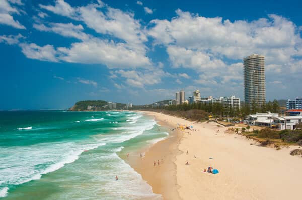 Aerial view of a bustling Gold Coast beach filled with tourists, highlighting the city's distinct tourist appeal in the blog post 'Is The Gold Coast Part of Greater Brisbane?'