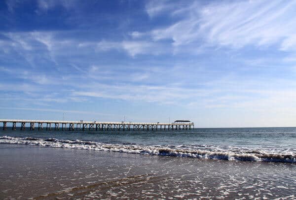 Jetty extending into the calm sea at Grange Beach, Adelaide, showcasing the serene coastal appeal in the Adelaide vs. Canberra travel debate