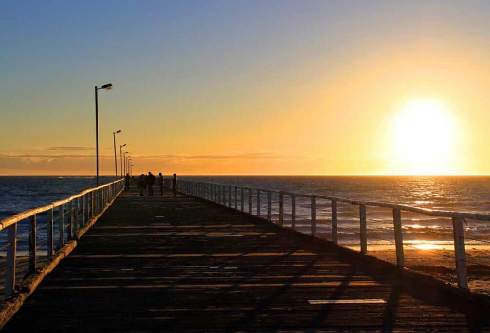 Sunset view from Semaphore Jetty in Adelaide, Australia, marking the end of daylight saving time with people walking along the pier