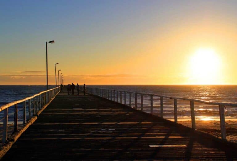 Sunset view from Semaphore Jetty in Adelaide, Australia, marking the end of daylight saving time with people walking along the pier