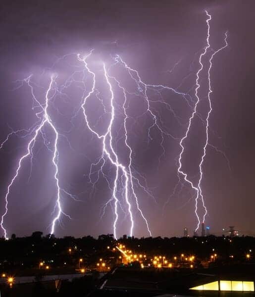Multiple lightning strikes illuminate the night sky over Melbourne, showcasing the city's skyline silhouetted in the distance. This image exemplifies the dramatic and unpredictable nature of Melbourne weather, tying into the blog post's discussion on 'why Melbourne weather is unpredictable'.