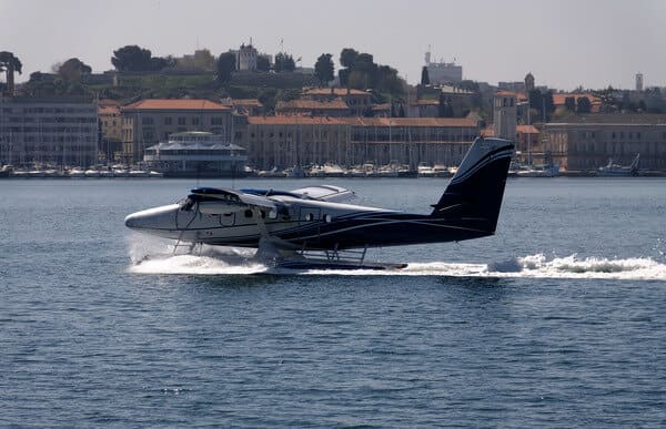 A seaplane making a romantic landing on the waters near Perth for Valentine's Day, with the city's skyline providing a picturesque backdrop, perfect for an adventurous couple's celebration.