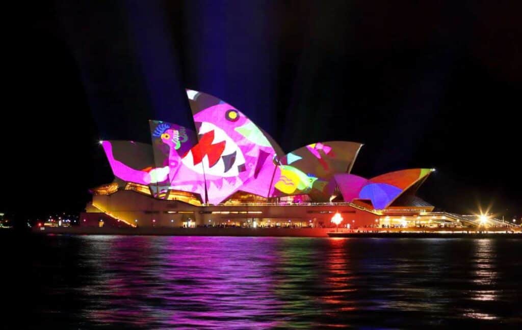 Sydney Opera House during Vivid Sydney festival, with colourful light projections on its sails, showcasing the city's love for arts and events, a cultural pro of living in Sydney.