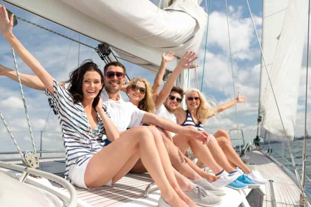 Joyful friends enjoying a private boat tour in Sydney, smiling and waving on the yacht's deck, encapsulating the intimate and fun experience of private boating in Sydney.
