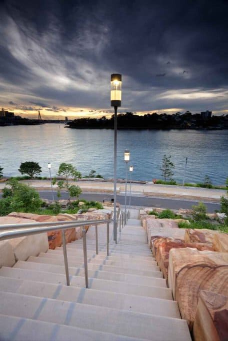 A serene dusk settles over Barangaroo, with a view of the illuminated steps leading to Sydney Harbour—a quintessential start to the 'Taste of Sydney' tour showcasing Barangaroo and The Rocks' culinary delights.