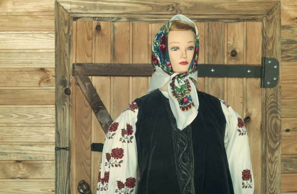 Mannequin dressed in traditional embroidered costume often used in rituals for Halloween, displayed against a rustic wooden background.