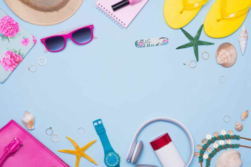 Summer concept. Pink handbag with accessories on light blue background