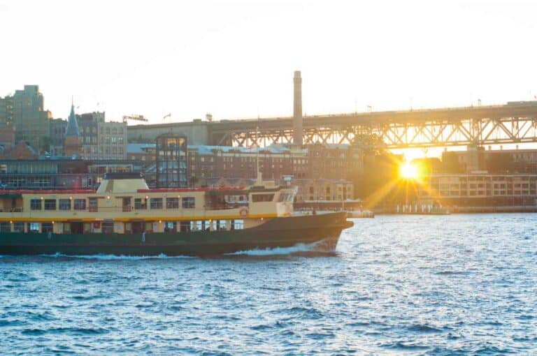 Sunset over Sydney's harbour with a ferry in the foreground, illustrating the ease of commuting and picturesque views as pros of living in Sydney.