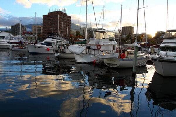 A serene marina in Hobart with boats moored in calm waters, reflecting the soft glow of the early evening sky. This peaceful setting captures the romantic atmosphere ideal for celebrating Valentine's Day in Hobart.