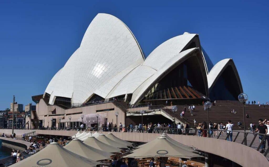 Crowds enjoying the sunny ambiance at a waterfront bar near the iconic Sydney Opera House, a popular spot on Sydney foodie tours for its spectacular views and gourmet dining options.