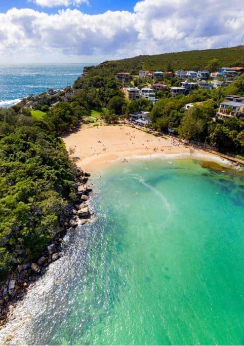 Aerial view of Manly and Shelly Beach in Sydney, highlighting the proximity to beautiful beaches as a key pro of living in Sydney, perfect for relaxation and water activities.