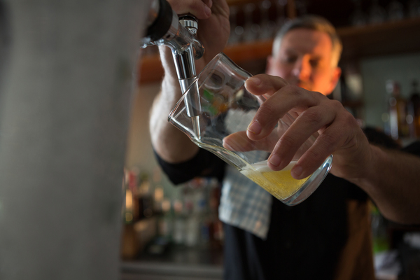 brewer filling beer in beer glass from beer pump