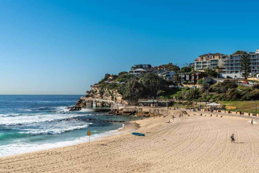 Bronte Beach in Sydney, Australia, with its golden sands and serene waves, framed by lush greenery and cliffside houses, a scenic spot often included in beach and food tour itineraries.
