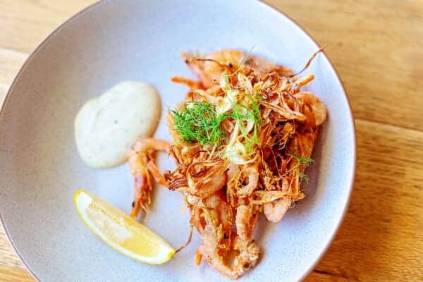 A gourmet dish of deep-fried prawns served with a lemon wedge and aioli, a perfect entree for couples looking for romantic things to do on Valentine's Day in Sydney, such as doing a cooking class.
