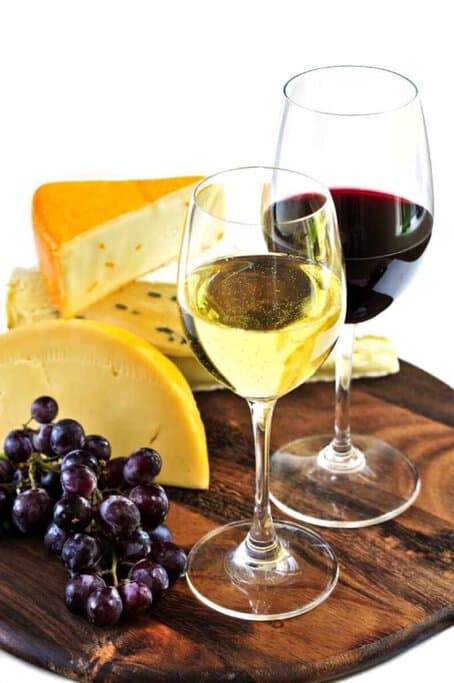 A selection of cheese with a glass of red wine and white wine, representative of the gourmet experiences on Hunter Valley wine tours from Sydney.