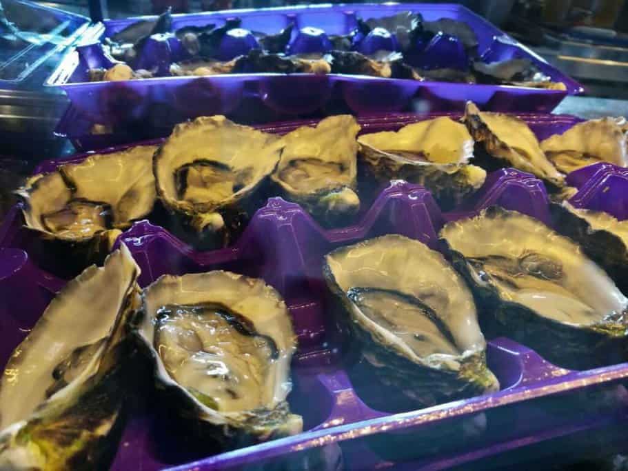 Freshly shucked Sydney rock oysters presented on a purple tray, a delicacy often featured on Sydney bites food tours for seafood lovers.