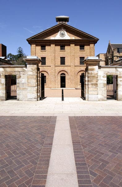 The historic Hyde Park Barracks in Sydney, captured on a clear day, showcasing its sandstone entrance and symmetrical architecture. This site is a popular stop on Sydney ghost tours, steeped in history and tales of the paranormal.