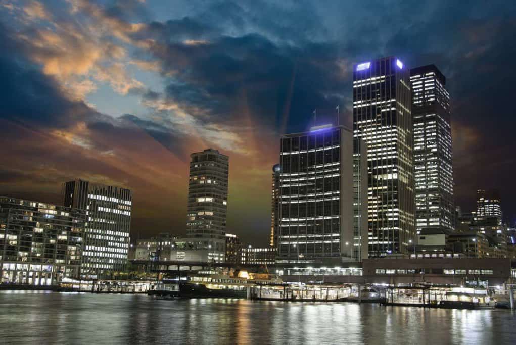 Sunset over Brisbane's cityscape, with modern office buildings illuminated as night falls. This image provides a contrast to Brisbane's typical weather conditions, relevant to the question 'does it snow in Brisbane,' highlighting the city's generally warm, snow-free climate.