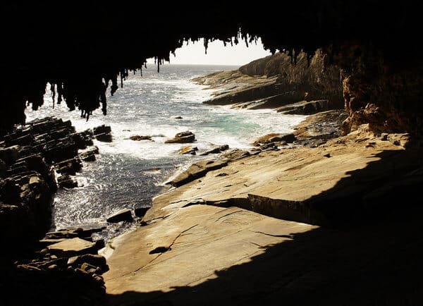 Stalactites hanging from the roof of a sea cave at Admiral's Arch on Kangaroo Island near Adelaide, with the sun glistening on the turquoise waters and layered rocks, creating a romantic natural setting for a Valentine's Day outing.