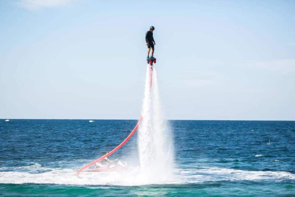A person performs an impressive stunt on a flyboard above the ocean, a high-flying experience comparable to bungee jumping over the Sydney Harbour Bridge.