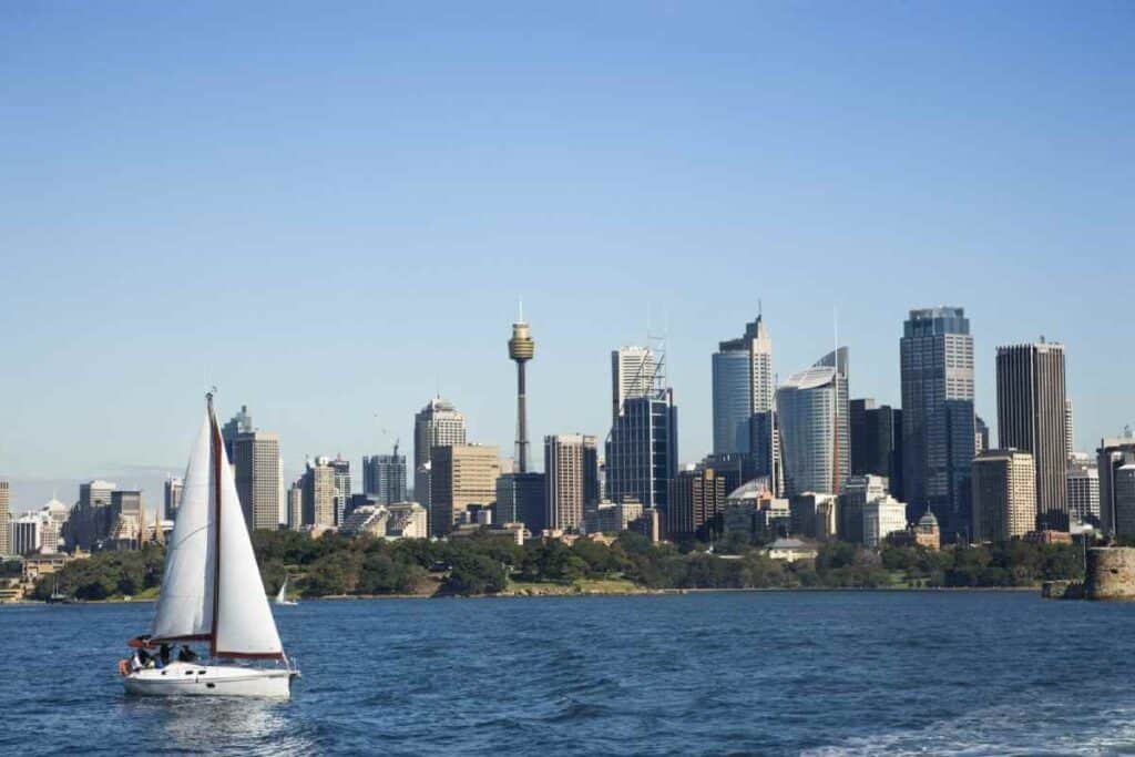 A private sailboat on a Sydney Harbour tour glides across the water with the city's skyline in the background, showcasing the exclusive experience of Sydney private boat tours.