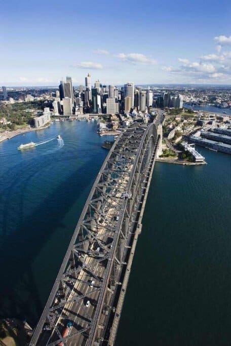 Aerial view of Sydney Harbour Bridge with city skyline, illustrating the bustling urban lifestyle as a con of living in Sydney due to traffic but also a pro for its connectivity and iconic landmarks.