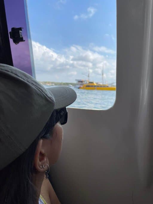 The author, Kate, sitting inside the Gili Getaway fast boat, gazing out at the sea and other boats, on their journey from Bali to the Gili Islands.