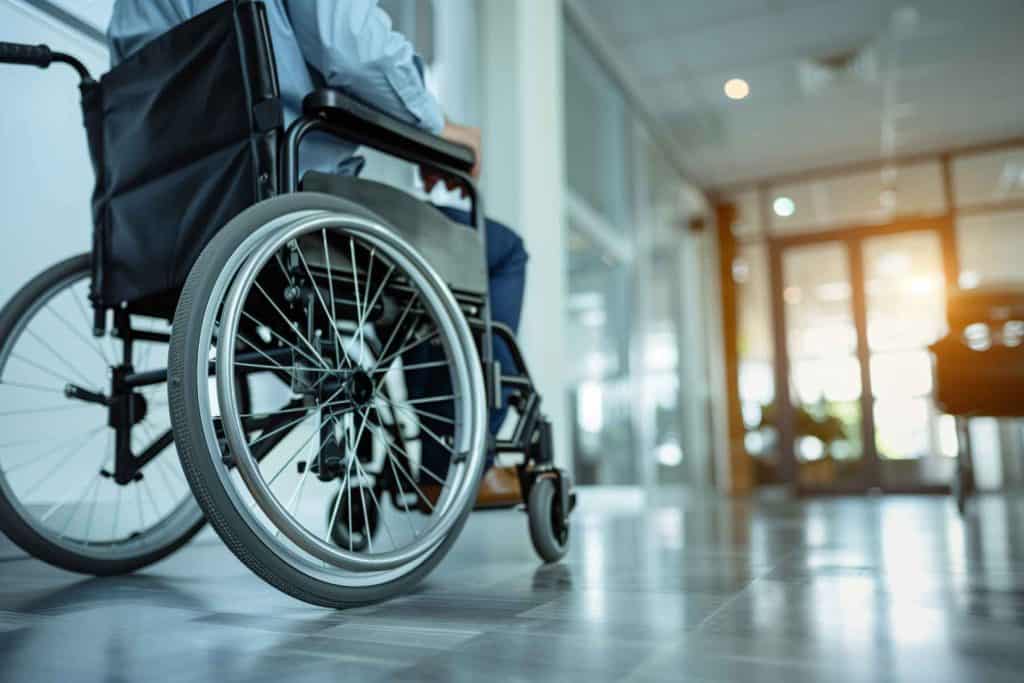 A man sitting in a wheelchair in a room, surrounded by walls and furniture.