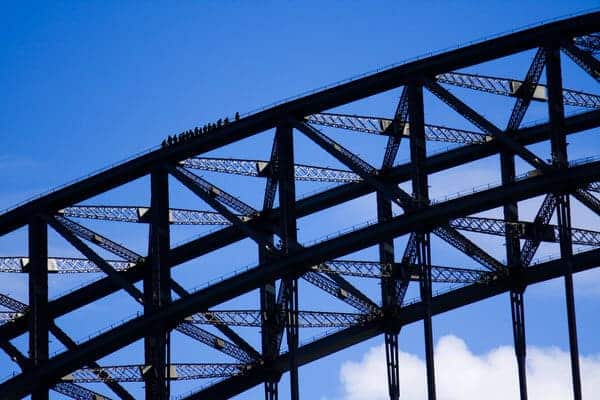 Silhouetted figures stand atop the iconic Sydney Harbour Bridge, while participating in a sky-high bridge climb adventure.