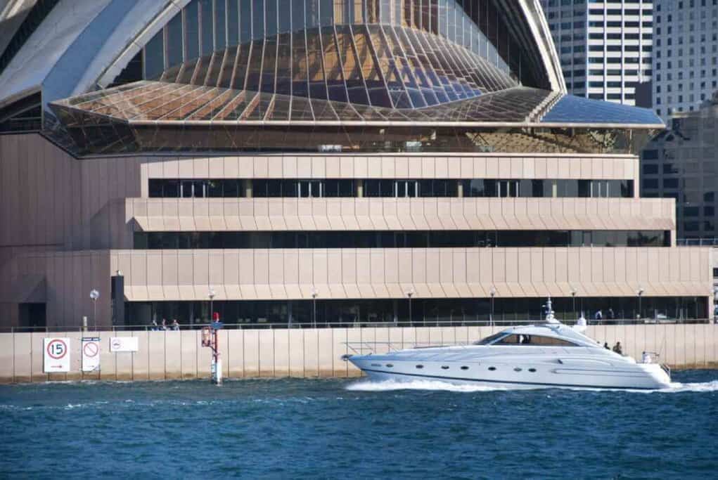 A luxury yacht from a Sydney private boat tour sails near the Sydney Opera House, highlighting the opulent and exclusive boating experiences available in Sydney.