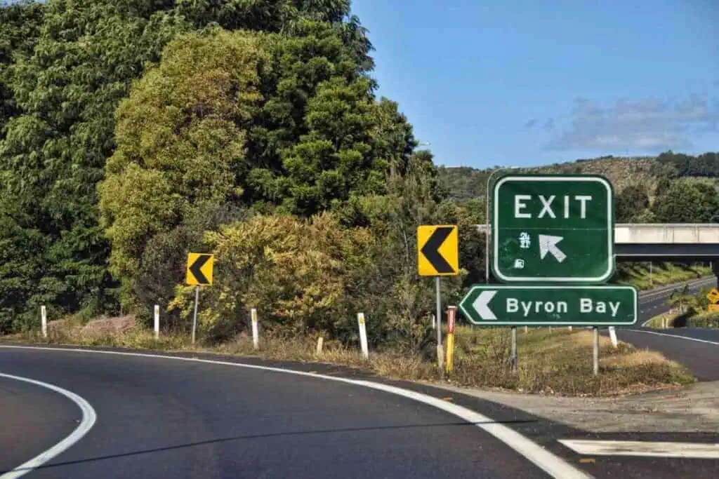 Highway exit sign for Byron Bay surrounded by lush greenery, representing a scenic stop on Australian road trips.
