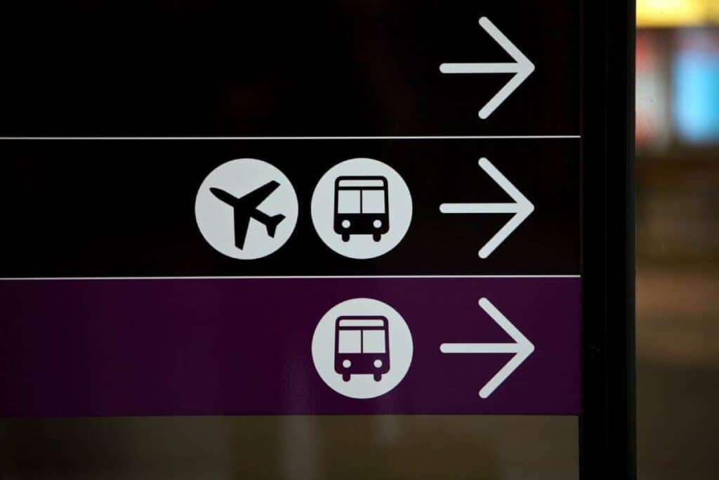 Directional signs at a transportation hub pointing towards airport and bus services, relevant for discussing how Ubers in Sydney provide an alternative travel option to traditional public transport.