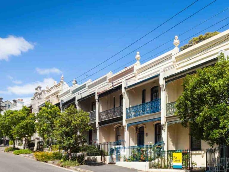 Row of charming terrace houses in Paddington, Sydney, representing the residential appeal as a pro of living in Sydney, balanced with the reality of property availability signified by a 'For Lease' sign.