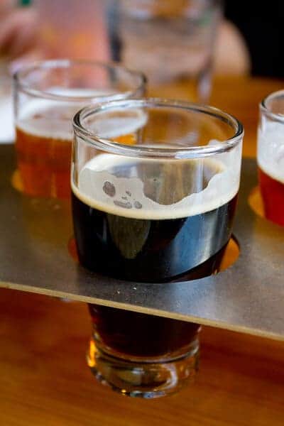 A close-up of a dark stout beer with a frothy head, part of a sampler at a brewery tour in Brisbane, showcasing the rich variety of craft beers available to explore.