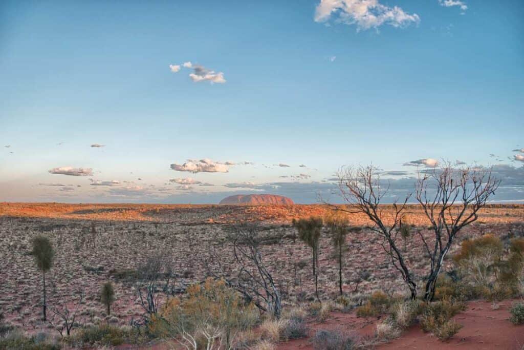 View of the expansive landscape in the Australian outback with Uluru in the distance, perfect for a road trip itinerary