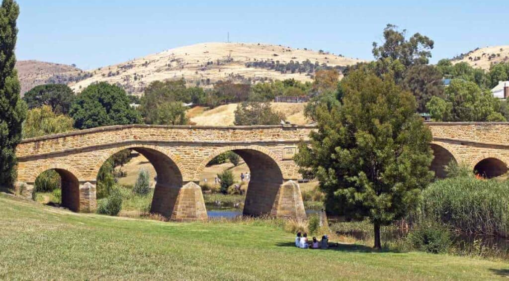 Historic stone bridge in Richmond, Tasmania, surrounded by lush greenery and hills, ideal for inclusion in an Australian road trip itinerary.