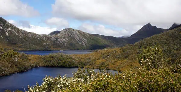 A serene view of Cradle Mountain National Park in Tasmania, showcasing the rugged mountain peaks and the reflective waters of Dove Lake. This image captures the natural beauty and tranquil atmosphere that one can experience on Cradle Mountain walking tours.