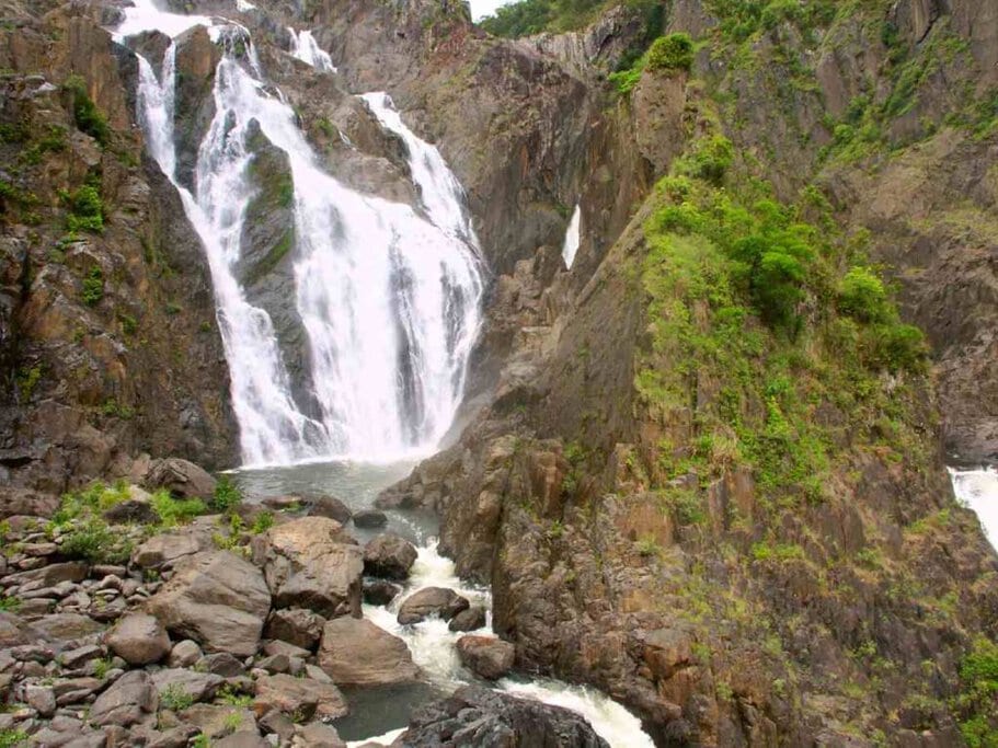 Majestic Barron Gorge waterfall cascading over rugged cliffs, a popular spot for water rafting near Port Douglas, showcasing the thrilling outdoor activities available for visitors.
