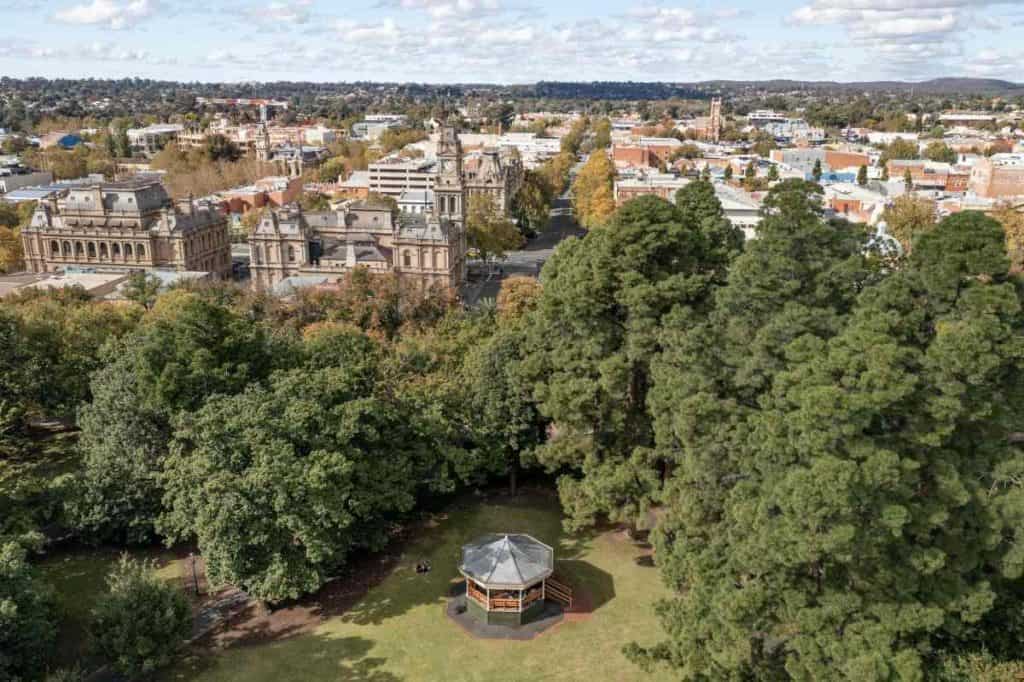 A panoramic view of Bendigo, Victoria, featuring historic architecture, lush greenery, and a gazebo in a public park. This image highlights the city's blend of heritage and natural beauty, showcasing aspects of lifestyle discussed in the blog post about the pros and cons of living in Bendigo.