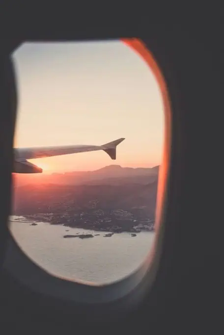 View of a sunset and mountainous landscape from an airplane window, capturing the feeling of adventure and exploration. This image is a perfect representation of finding the best Australia travel deals for those looking to explore the country.