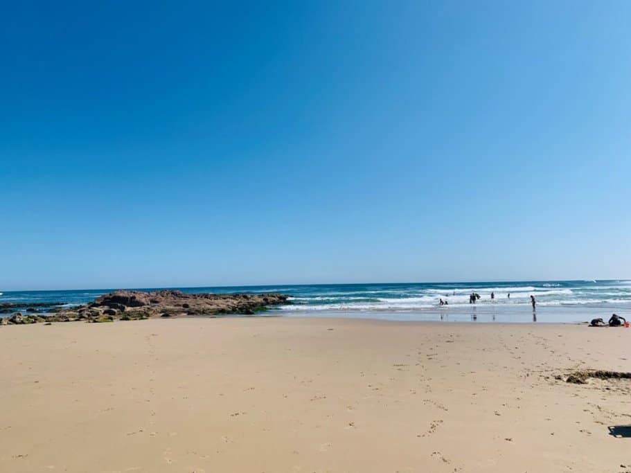 A sunny view of Birubi Beach in Port Stephens, showcasing its sandy shore and gentle waves, with people enjoying the water—one of the best beaches in Port Stephens known for its relaxing atmosphere and scenic beauty.