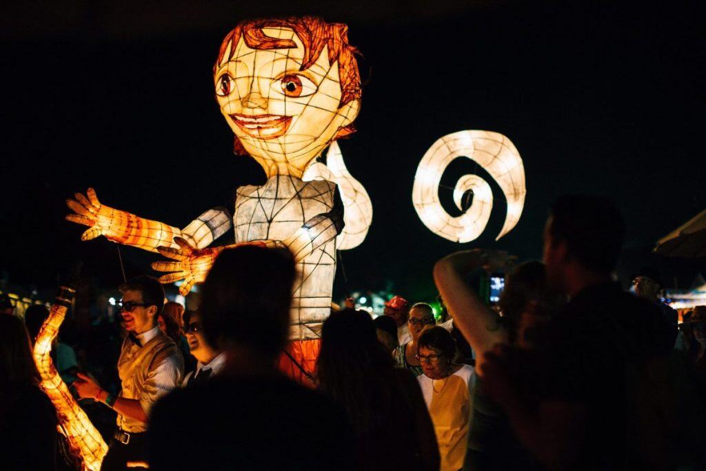 Crowd gathered around a giant glowing puppet and lantern sculptures at night during a lively celebration, capturing the creative spirit and community vibe of Australia’s most iconic festivals.