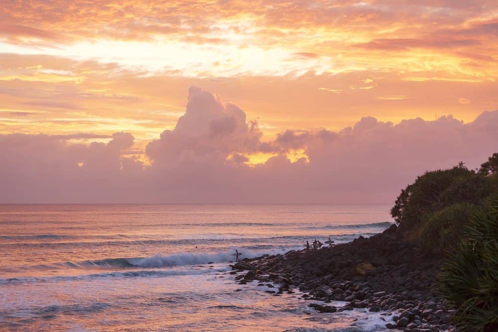 Golden sunset over Burleigh Heads, Queensland, with vibrant orange clouds reflecting off the ocean. This serene coastal scene highlights one of the best spots to experience must-see sunsets in Australia, tying into the blog post about top sunset locations.