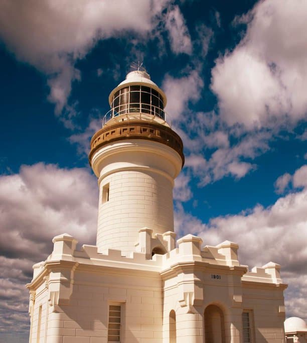 Cape Byron Lighthouse under a bright blue sky with scattered clouds, one of the top landmarks featured in many guides on things to do in Byron Bay.