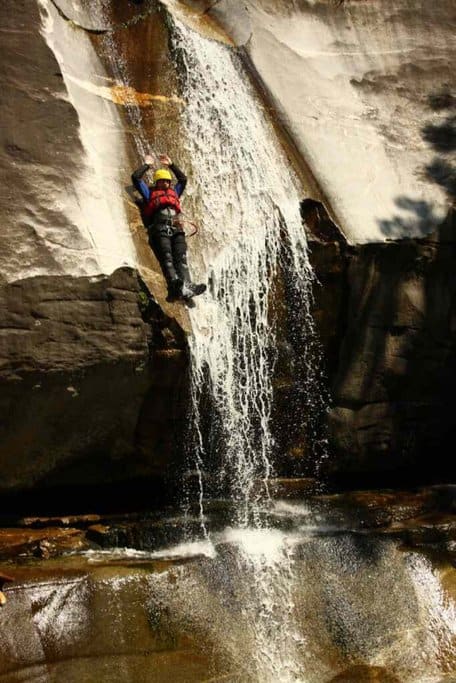 A person descending a waterfall while canyoning in the Blue Mountains, showcasing the thrilling adventure activities available in the region. This image relates to Blue Mountains travel deals, highlighting the unique outdoor experiences that can be included in travel packages.