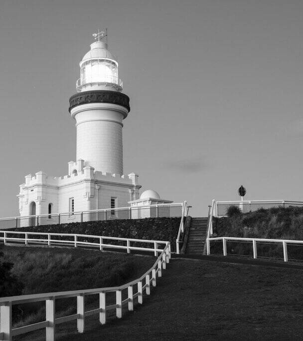 Black and white image of Cape Byron Lighthouse standing tall at the most easterly point of mainland Australia, a must-visit landmark during any scenic drive from Sydney to Byron Bay.