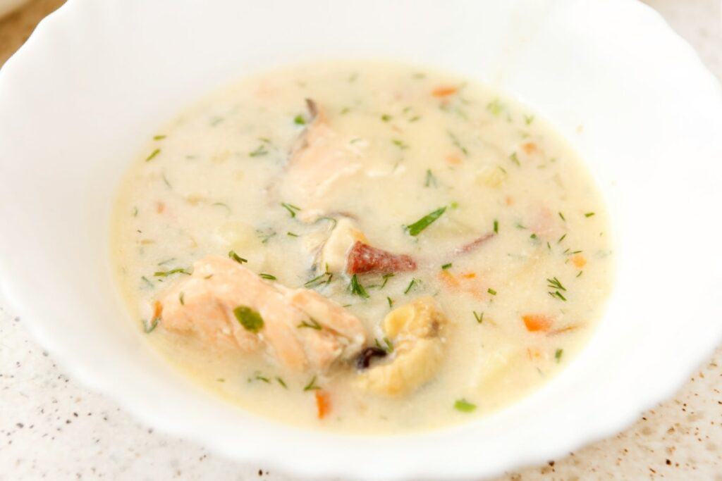 Close-up of a creamy seafood chowder garnished with fresh herbs, served at Sandpipers Restaurant, one of the best dining spots in Port Stephens, known for its fresh seafood dishes. This dish highlights the restaurant's reputation as one of the best places to eat in Port Stephens, offering local seafood in a cosy setting.