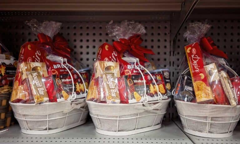 Three white Christmas hampers filled with various festive treats like nougat bars, shortbread, and biscuits, wrapped in clear plastic with red bows. These hampers represent popular gift ideas for Christmas in Australia, showcasing an assortment of snacks that are commonly found in Australian Christmas hampers.